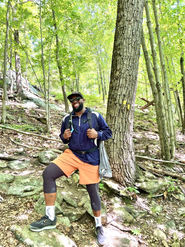 Black man hiking in the woods turns and smiles for the camera